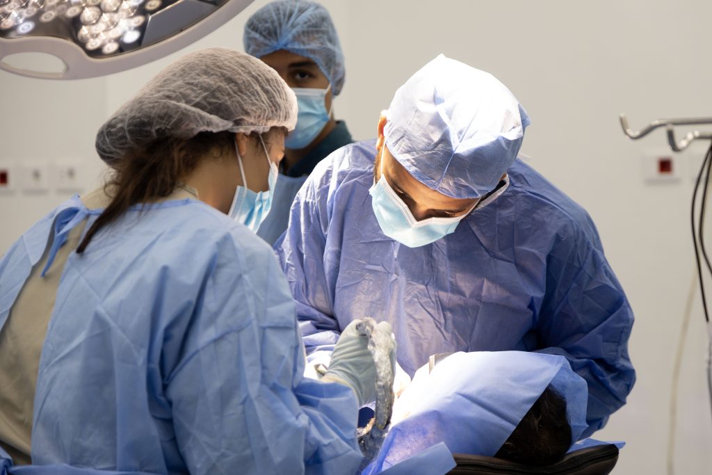 3 doctors in a hospital doing a dental implants live surgeries